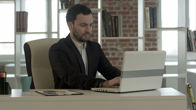 Happy business man finished his work in office with notebook