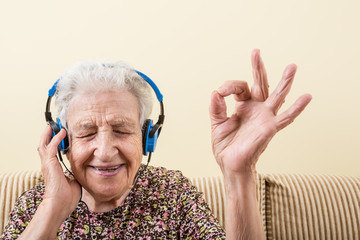 senior old woman listening music with headphone - obrazy, fototapety, plakaty