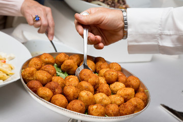 Persone che prendono le crocchette di pesce in un buffet