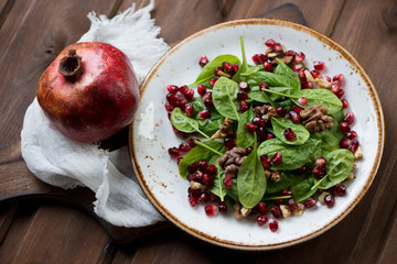 Fresh spinach, pomegranate seeds and walnuts salad, close-up