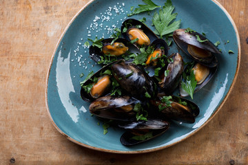 Turquoise plate with steamed mussels, salt and parsley, top view