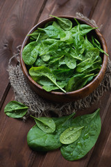 Fresh spinach leaves in a wooden bowl, close-up, studio shot