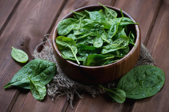 Wooden bowl with fresh spinach, selective focus, studio shot