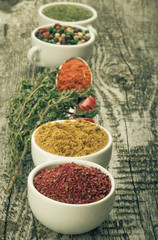 White ceramic cups with different kinds of spices, metal spoon,