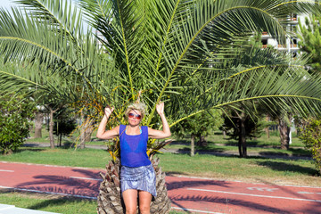 Happy woman in sunglasses posing near a palm