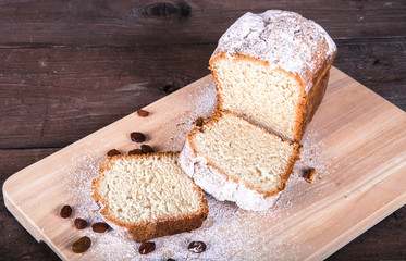 Cake with raisin and sugar powder on the wooden table. Selective