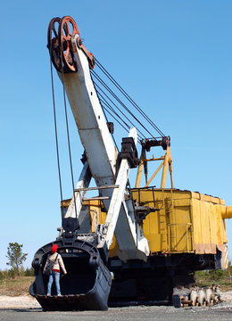 A child stands in the old excavator bucket without tracks