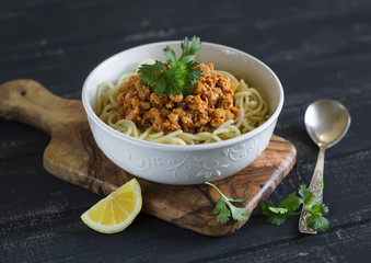 spaghetti with meat Bolognese sauce in a white bowl on a dark wooden background