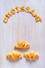 Croissants and letters of dough on the wooden table