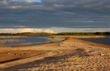 Fototapeta na wymiar Picturesque sandy spit on forest lake. Karelia, Russia.