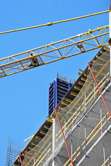 Crane and building construction site against blue sky