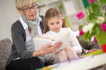 girl interested looks at the book while grandma  read