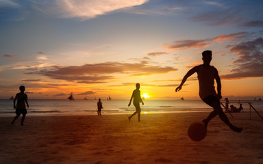 Sunset silhouettes playing beach football