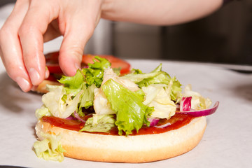 Salat auf das Burger Brötchen legen