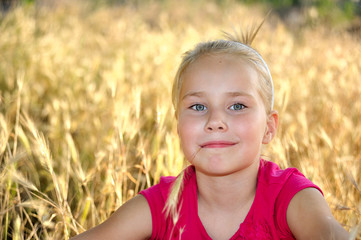Smiling girl  on the meadow looking right at camera
