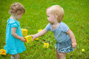 Little girls on nature playing toy