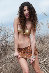 Model posing sexy in designers animal printed mini skirt in the reed zone of the sea - obrazy, fototapety, plakaty
