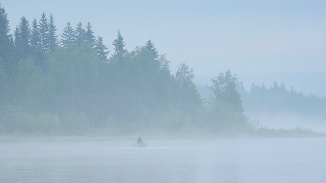 Fisherman on the foggy forest lake. 4K UHD video.