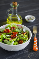 salad with fresh vegetables, garden herbs and sun-dried tomatoes in a white bowl 