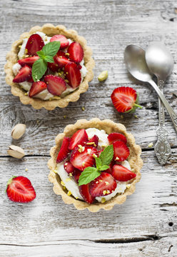 tartlets with cream cheese and strawberries on a light wooden background