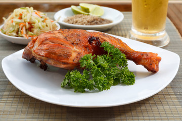 Grilled chicken on white plate with parsley, salad and beer outdoors