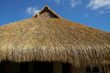 Fototapeta na wymiar Traditional African thatched roof agaisn a blue sky