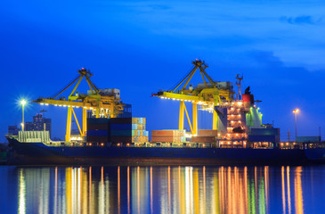 Container Cargo freight ship with working crane loading bridge in shipyard at dusk for Logistic Import Export background