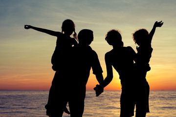 Silhouette of happy family who playing on the beach at the sunse