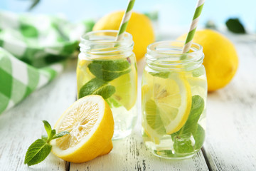 Fresh lemonade with lemon on white wooden background