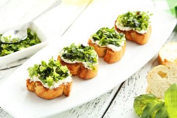 Tasty fresh bruschetta on plate on white wooden background