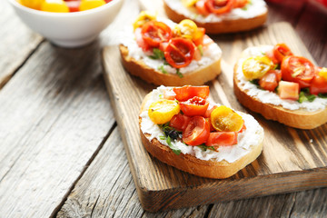 Tasty fresh bruschetta with tomatoes on cutting board on grey wo