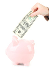 Female hand putting coin into pink piggy bank
