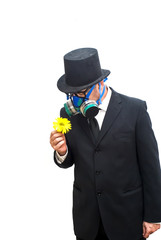 Businessman with gas mask and hat looking at an flower in his hand