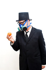 Businessman with gas mask and hat looking at an apple in his hand