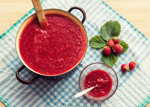 Homemade strawberry jam (marmelade) cooking. Large pot with hot jam and fresh strawberries