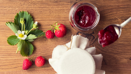 Homemade strawberry jam (marmelade) in jars on wooden background.