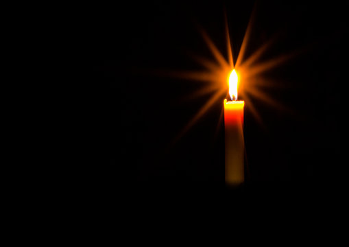 One candle burning brightly in the dark.