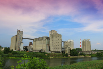 Fototapeta na wymiar Old factory with silo tanks for corn near river