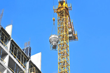 Naklejka premium Crane lifting concrete mixer container against blue sky