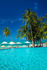 Fototapeta na wymiar Large infinity swimming pool on the beach with palm trees