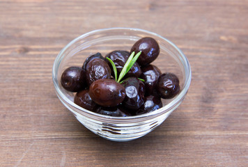 Black olives on bowl on wooden table