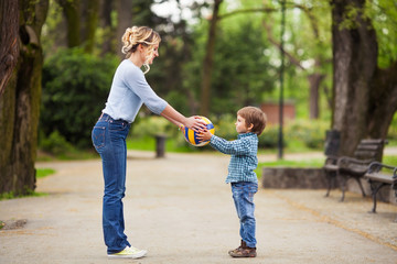 Fototapeta premium Young mother and her little son playing in a park