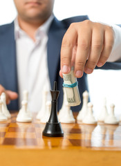 Closeup of businessman playing with twisted dollars at chess gam
