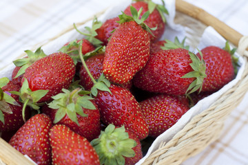 Fresh strawberries with green tails wickerwork basket with white napkin