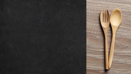 Wooden Spoon and Fork on wood Table with side is Black place mat. Menu Set Concept