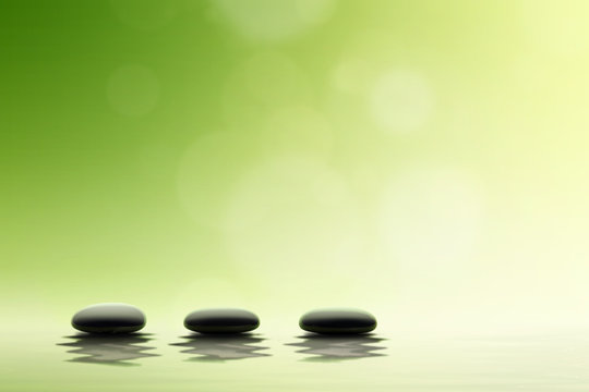 Spa concept. Black spa stones on green background.