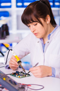 Woman with a tester and a printed circuit board