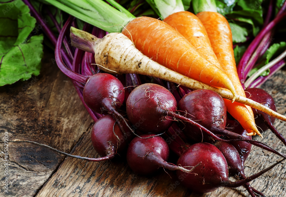 Wall mural fresh organic beets and carrots on old wooden table, selective f