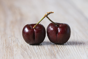Two cherries over wooden background