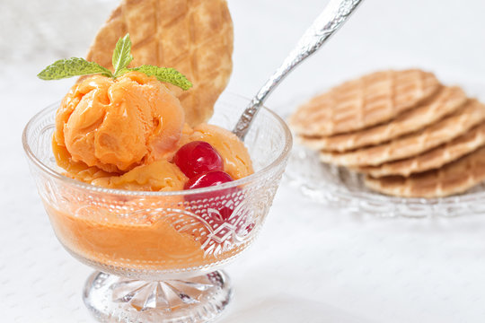 Orange ice crem served in a cup with waffles